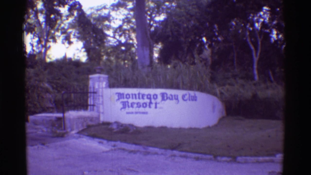 1971 8mm Hawaii travel frame showing the Montego Bay Club Resort entrance sign, gate, stone post, trees, and roadside verge.