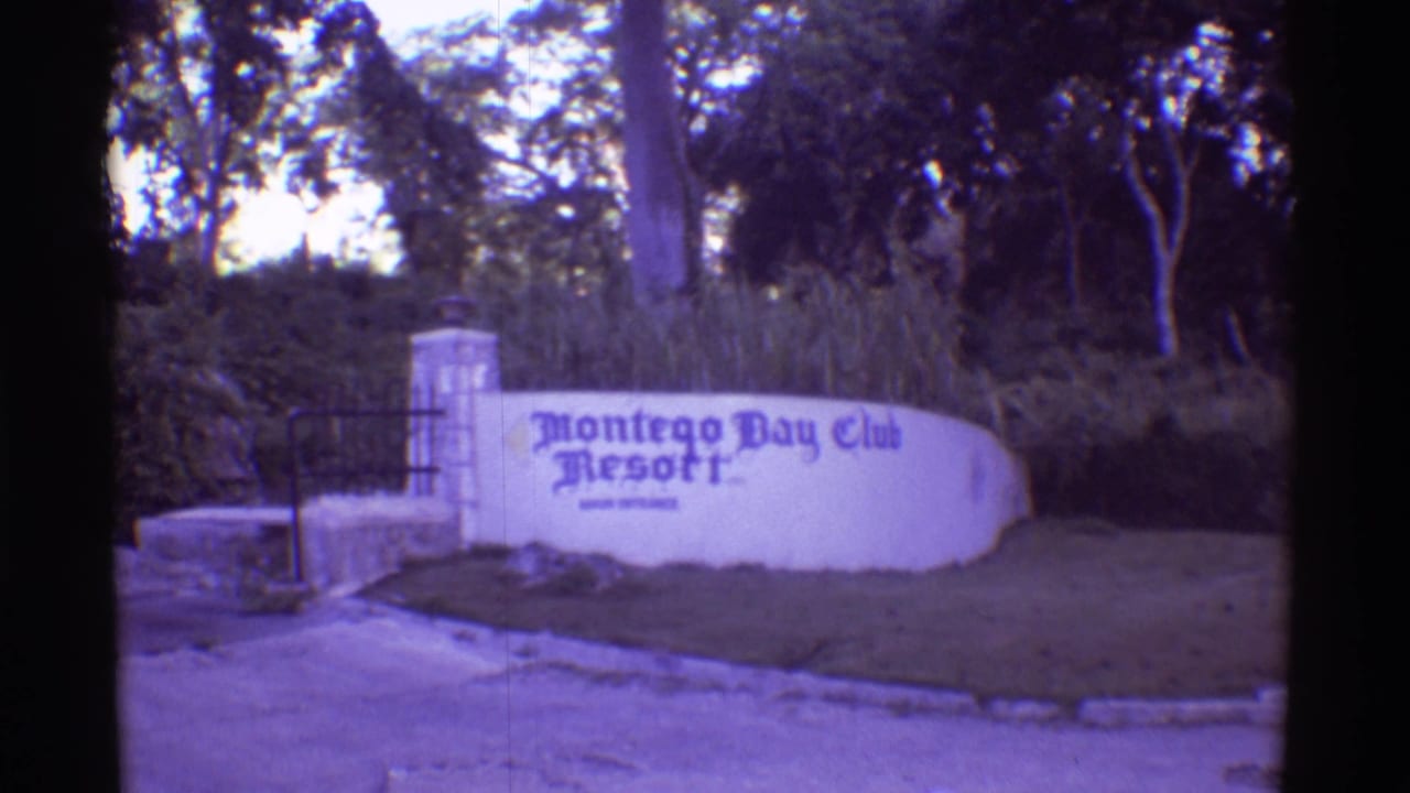 1971 Hawaii 8mm frame showing the Montego Bay Club Resort entrance sign on a white curved wall near a gate and shaded trees.