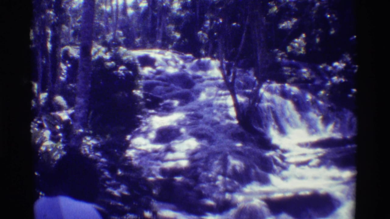 Rocky forest stream with small waterfall drops and dark 8mm film borders.
