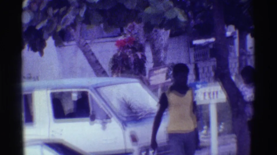 1971 Hawaii street view with a man in a yellow tank top passing a white van near an Inn on the Beach sign.