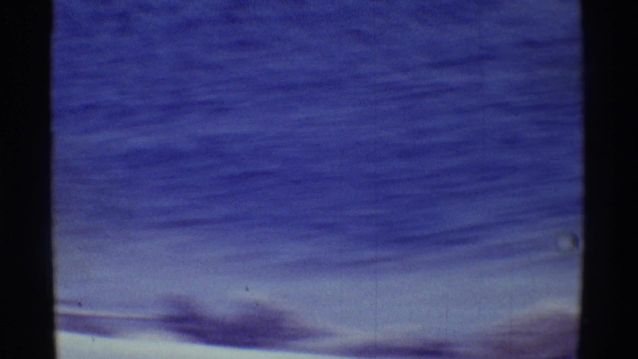 Blue ocean and pale sky divided by a dark vertical film edge.