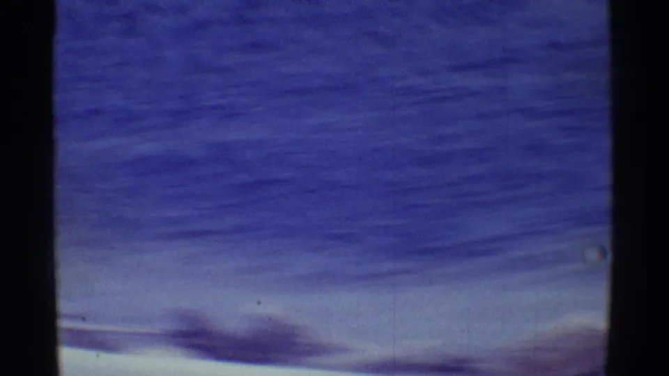 1971 Hawaii 8mm frame with blue ocean, hazy sky, soft cloud band, and dark gate edge from the scanned film.