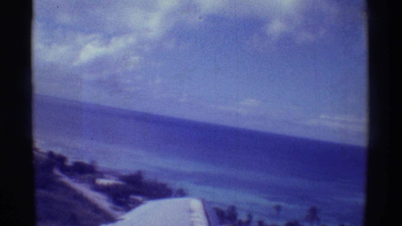 Aerial view of ocean and shoreline from a plane window with wing in foreground.