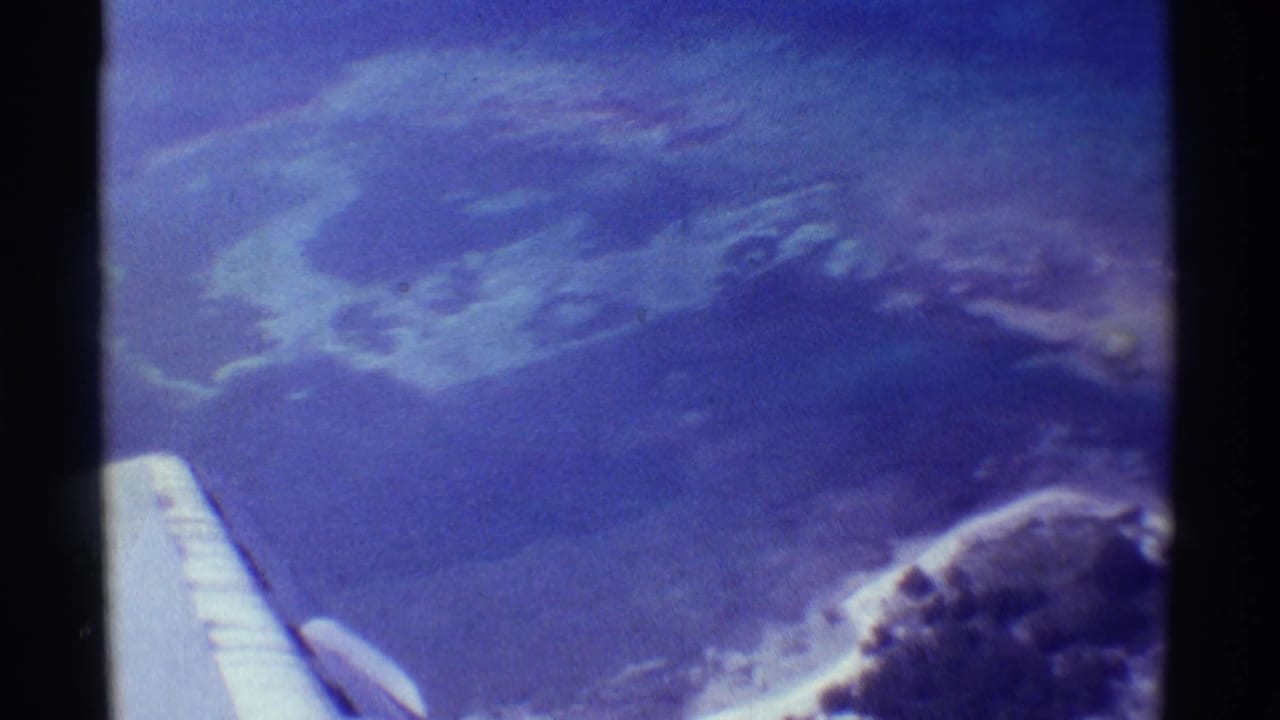 Aerial view of hazy volcanic landscape with airplane wing visible at lower left.