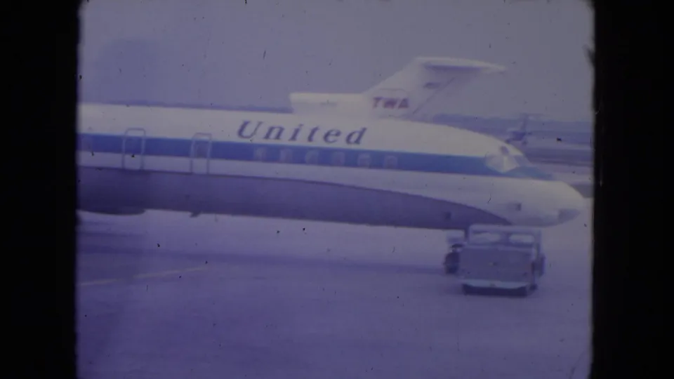 1972 O'Hare home-movie frame showing a United aircraft on the ramp, with a TWA tail visible in the background.