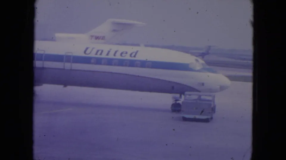 1972 O'Hare frame with United lettering on an aircraft fuselage and a ramp vehicle positioned near the nose gear.