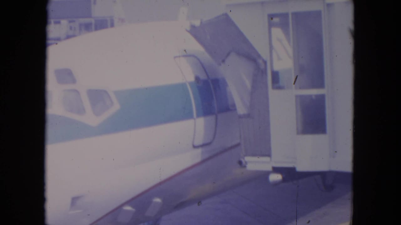 Aircraft nose beside a boarding structure with the cabin door area visible.