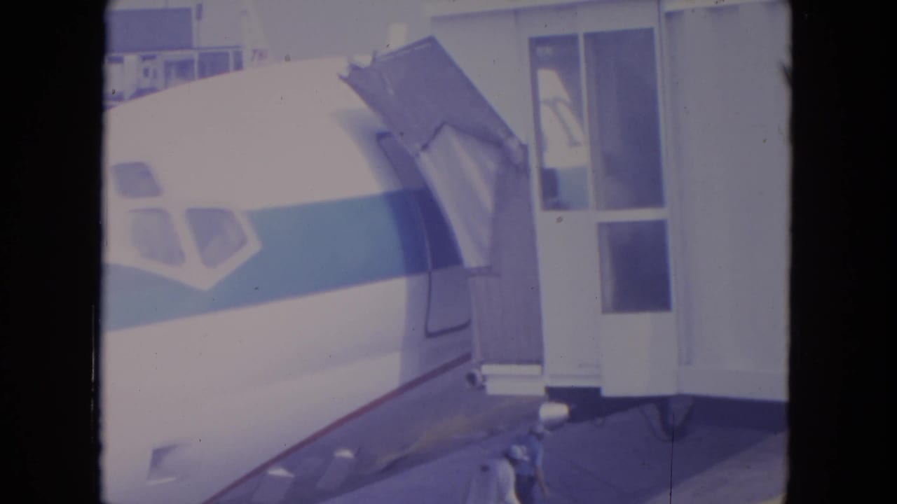 1972 O'Hare frame with the aircraft cockpit windows, blue stripe, and boarding structure filling most of the frame.