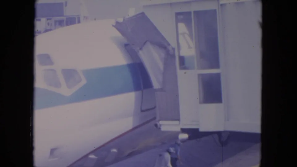 1972 O'Hare frame with the aircraft cockpit windows, blue stripe, and boarding structure filling most of the frame.