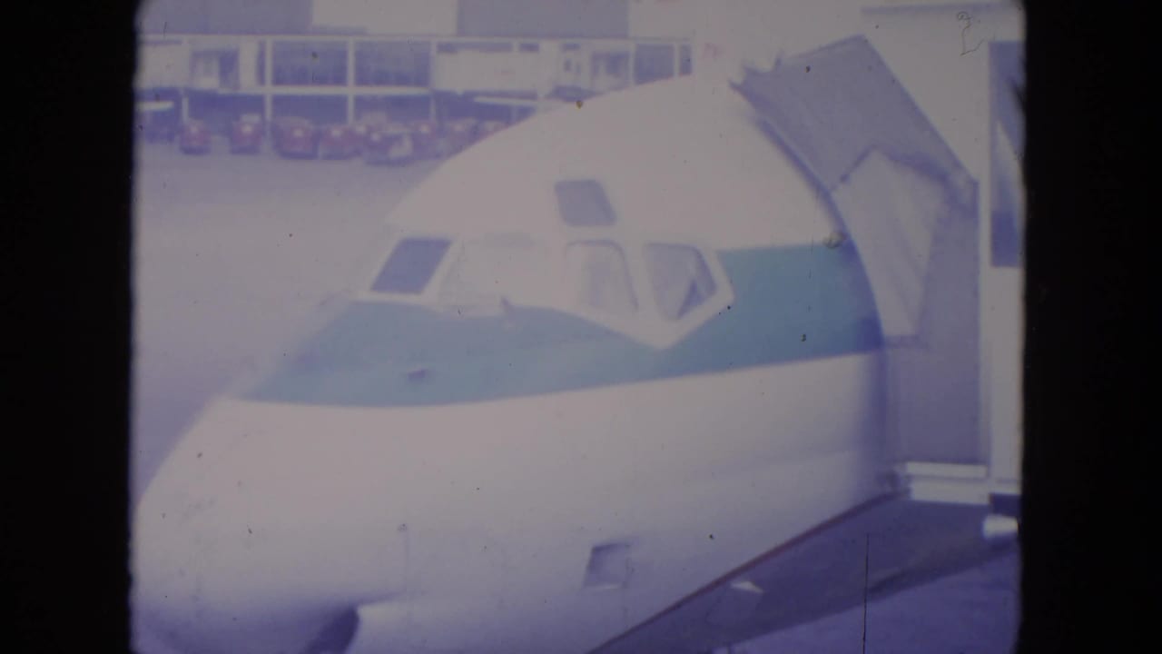 1972 O'Hare frame of the aircraft nose and blue stripe as the jet bridge remains aligned near the forward door area.