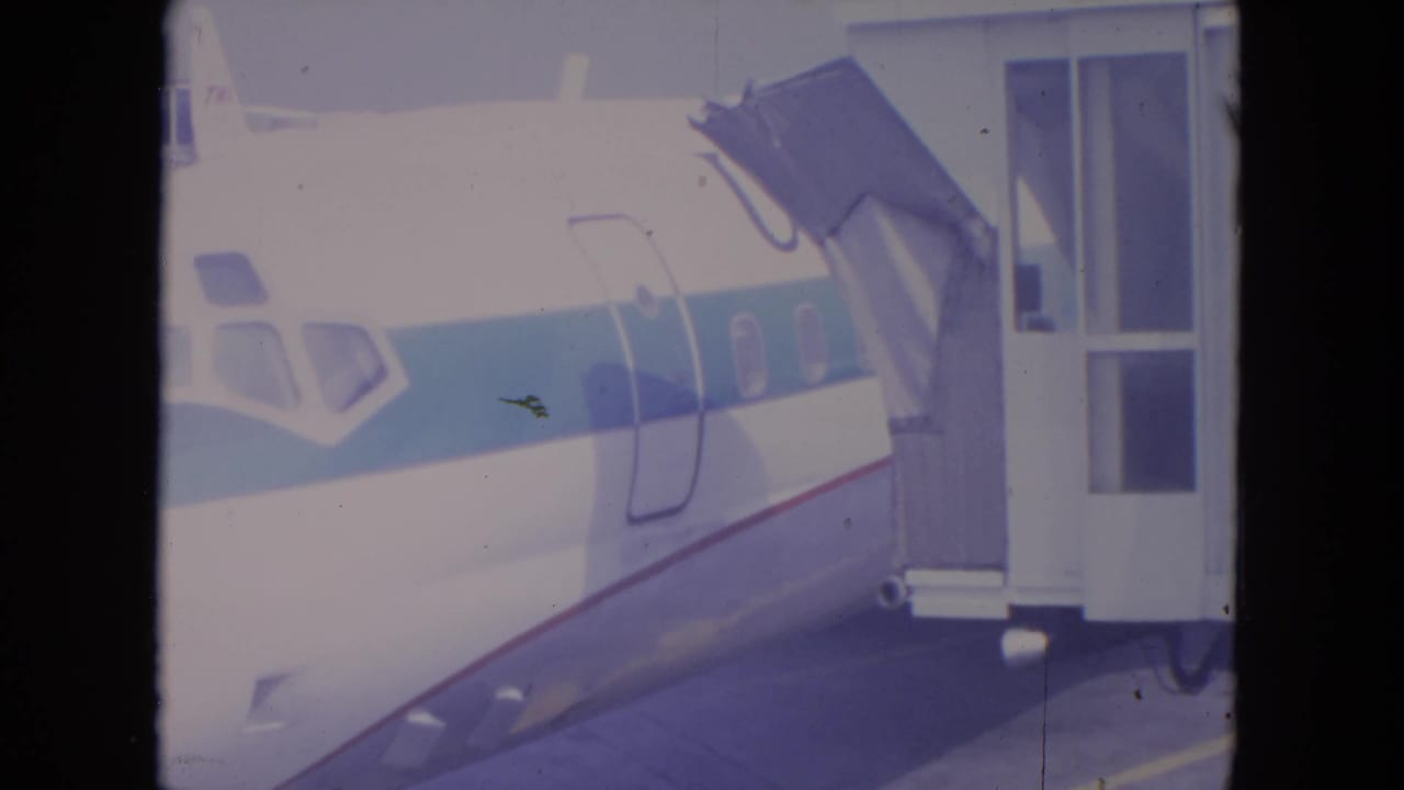Airplane fuselage and passenger door area aligned with a jet bridge.