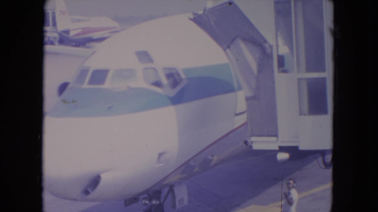 Commercial jet nose beside a connected jetway with a person near the lower right.