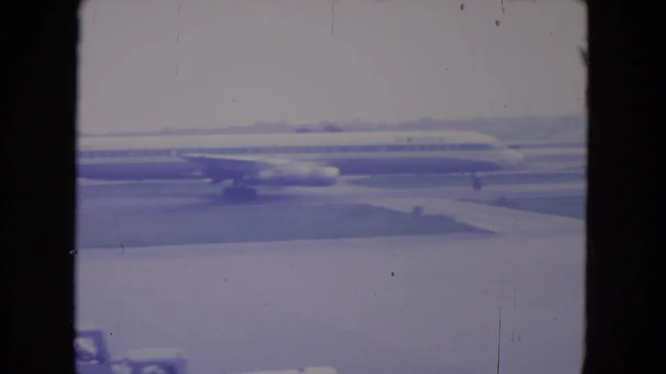 Side view of a United Airlines passenger jet on the O'Hare tarmac, with soft 8mm color and visible film wear.
