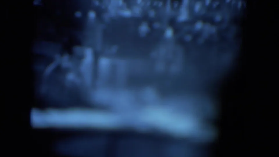 Blurry 1972 O'Hare Chicago 8mm frame showing indistinct screen-like content with heavy blue cast and dark film borders.