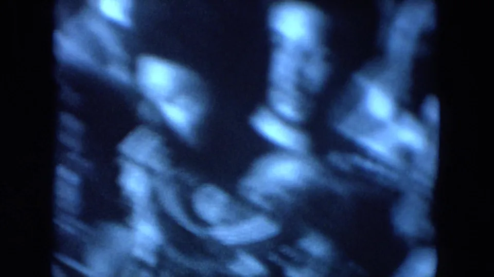 Blue-tinted 8mm frame from a 1972 O'Hare Chicago gathering showing people clustered in a crowd, with faces partly obscured by blur.