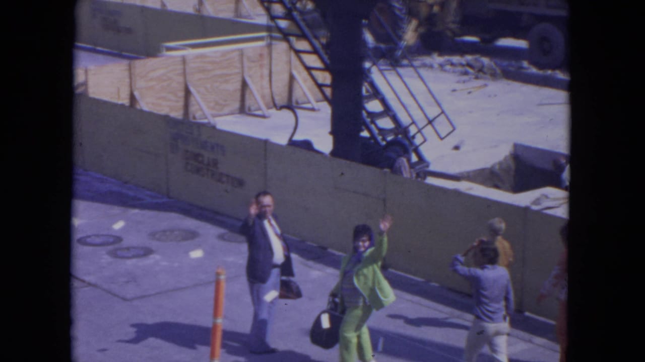 At O'Hare Chicago in 1972, pedestrians beside a construction barrier notice the camera and raise their hands in greeting.