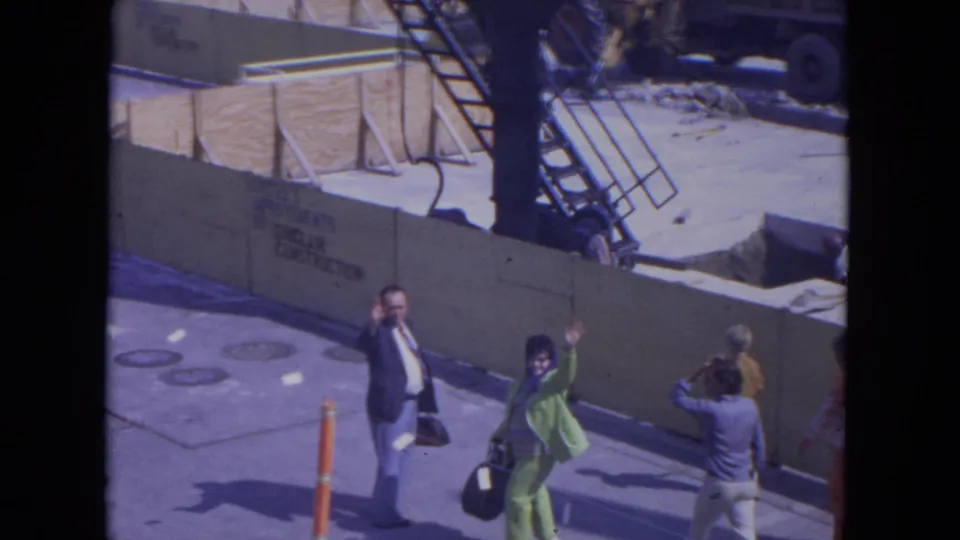 At O'Hare Chicago in 1972, pedestrians beside a construction barrier notice the camera and raise their hands in greeting.