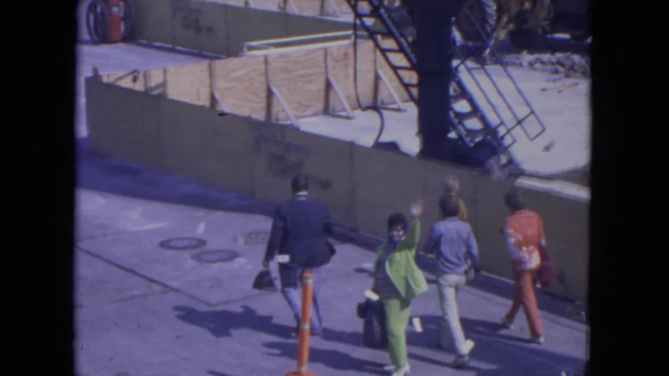 At O'Hare Chicago in 1972, a small group walks along the street while a woman in green and others wave toward the camera.