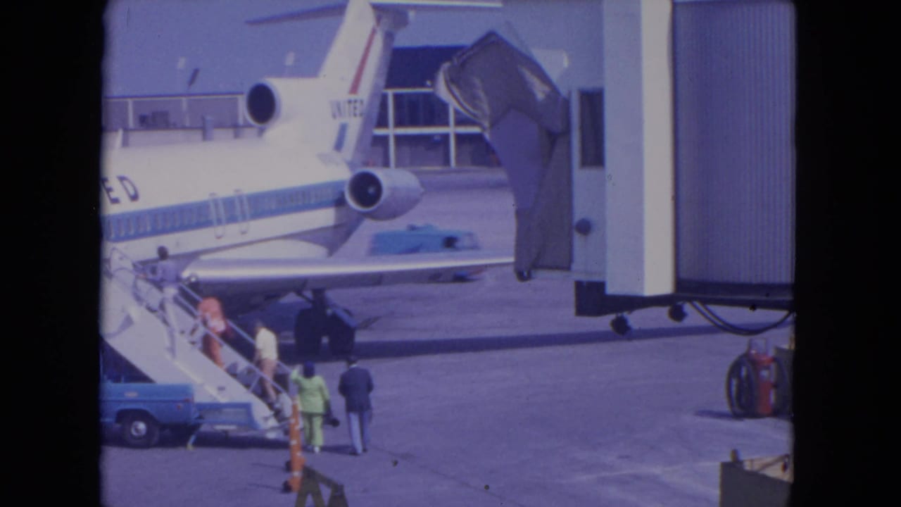 Passengers approach mobile stairs beside a United jet on the airport apron.