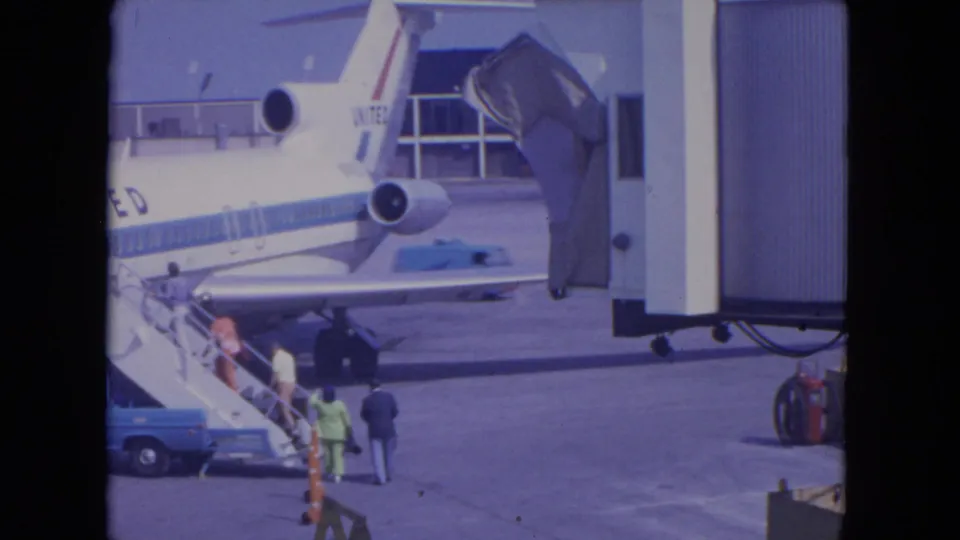 Passengers at O'Hare in 1972 approach mobile boarding stairs beside a United Airlines jet on the apron.
