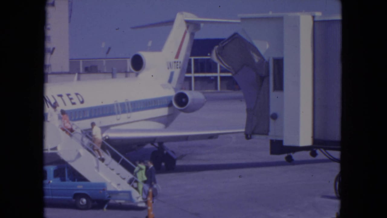 Passengers climb mobile stairs beside a United Airlines jet at an airport gate.