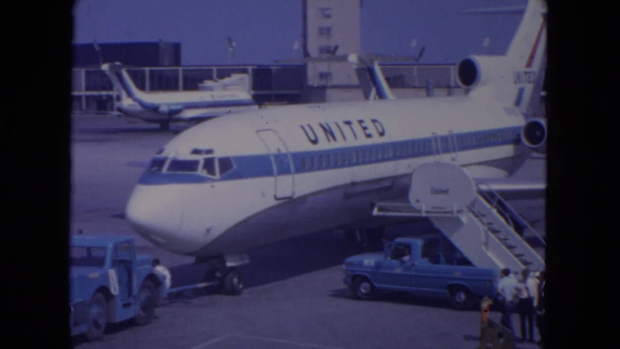 United Airlines aircraft at O'Hare in 1972 with mobile stairs attached and small groups of people visible near ramp vehicles.