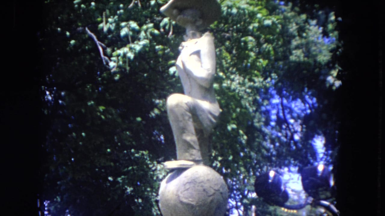 A stone sculpture is seen through soft 8mm color and dense greenery in the 1972 Mississippi River travel footage.