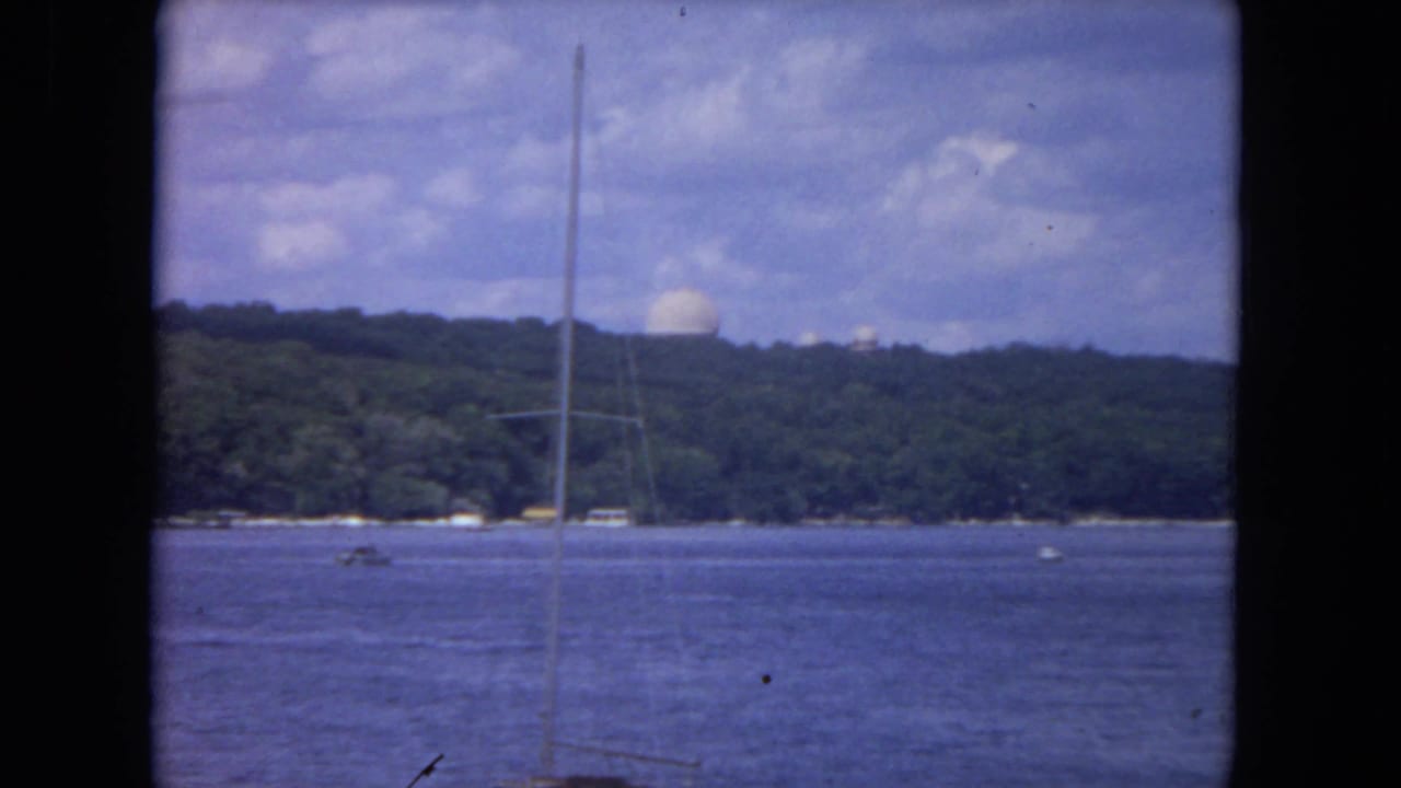 Mississippi River 8mm frame with a foreground sailboat mast, calm water, distant wooded ridge, and a white dome under clouds.