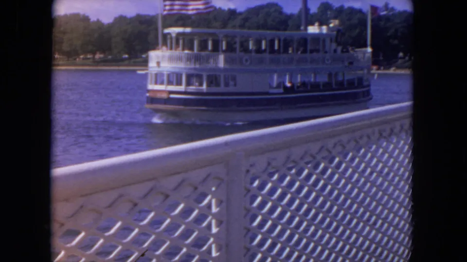 1972 8mm view of a white Mississippi River excursion boat moving past a decorative dock or boat railing.