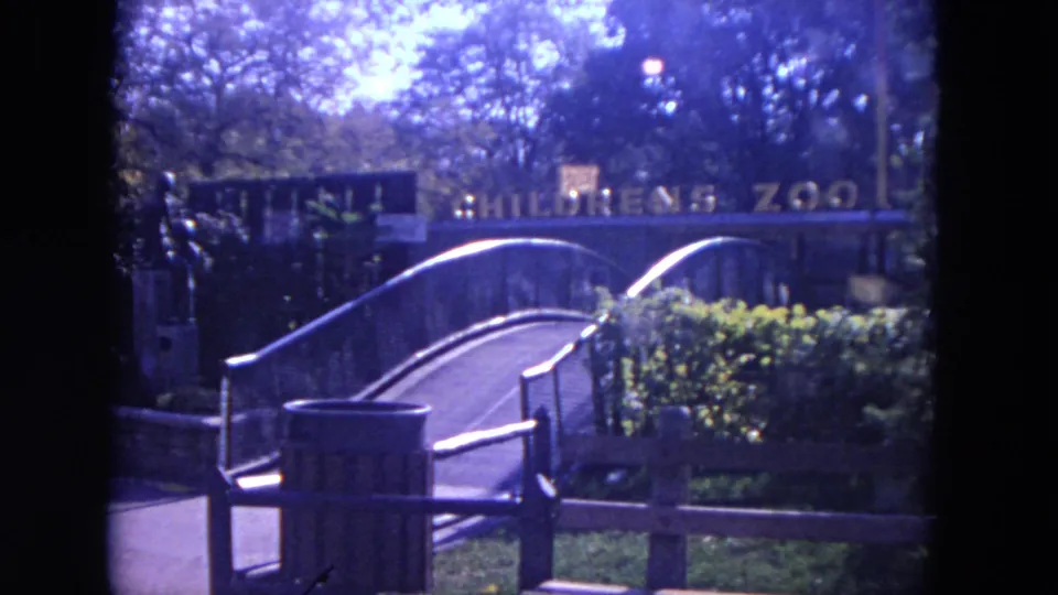 Visitor-shot 1972 Lincoln Park Zoo entrance view, showing the Children's Zoo sign, arched bridge, railings, and surrounding greenery.