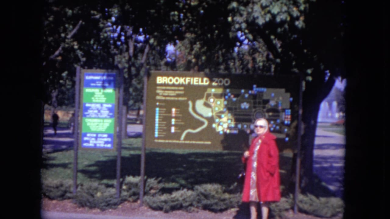 Woman in a red coat standing by a Brookfield Zoo map sign.