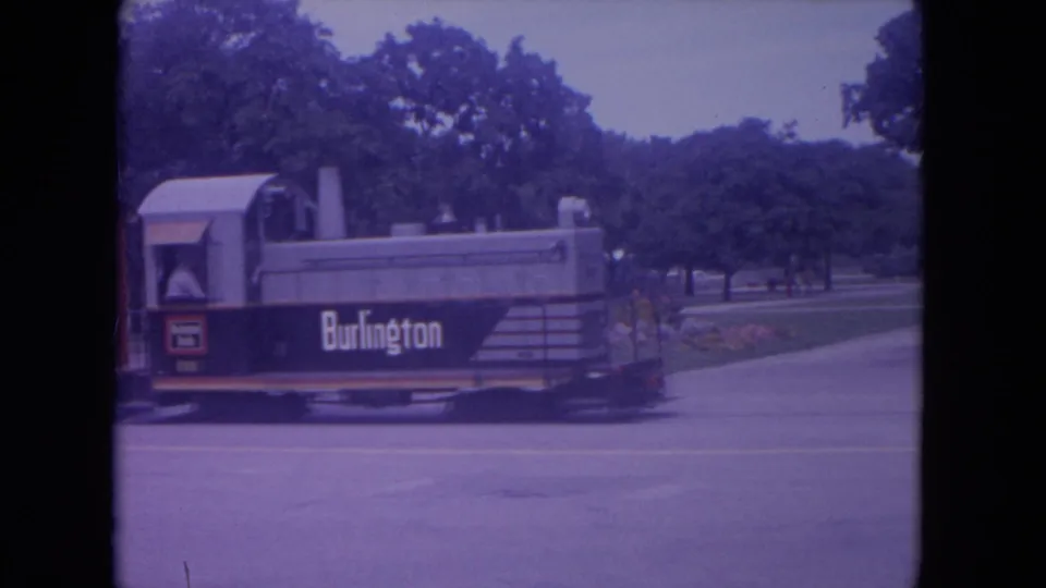 The Burlington-marked train is seen in a closer 1972 Lake Geneva view, moving beside a paved street and landscaped trees.