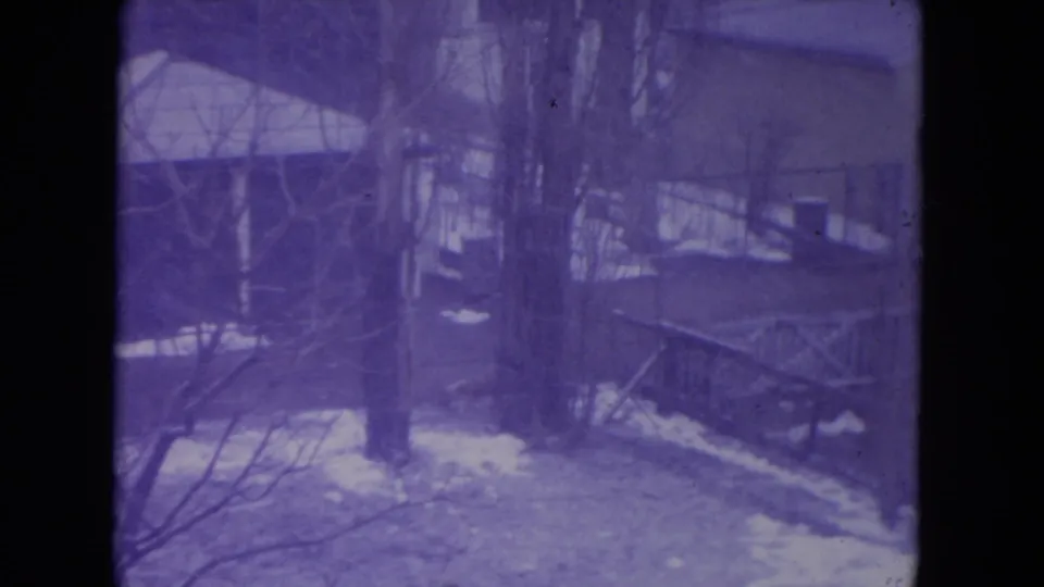 1972 Racine, Wisconsin 8mm frame showing a snowy residential yard with bare trees, fencing, and a small outbuilding.