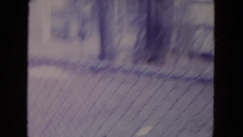 A blurred 8mm frame shows chain-link fencing, bare trees, and a residential yard in Racine, Wisconsin.
