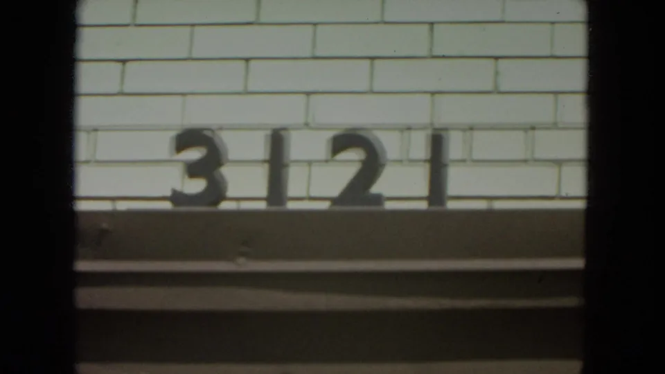 Building number 3121 on a white brick exterior in the 1972 Racine, Wisconsin 8mm home-movie clip.