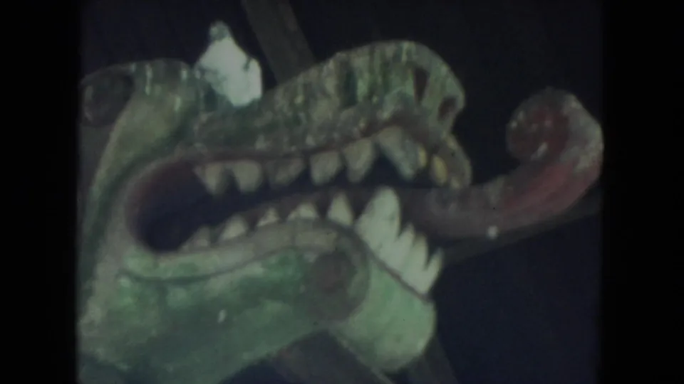 Close view of a painted dragon-like or gargoyle-like head with teeth and tongue in the 1972 Racine home-movie clip.