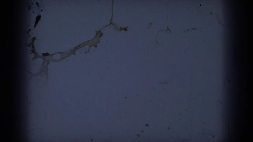 Scanned 8mm frame with little visible subject detail, showing dark blue exposure, dust, scratches, and heavy film-edge borders.