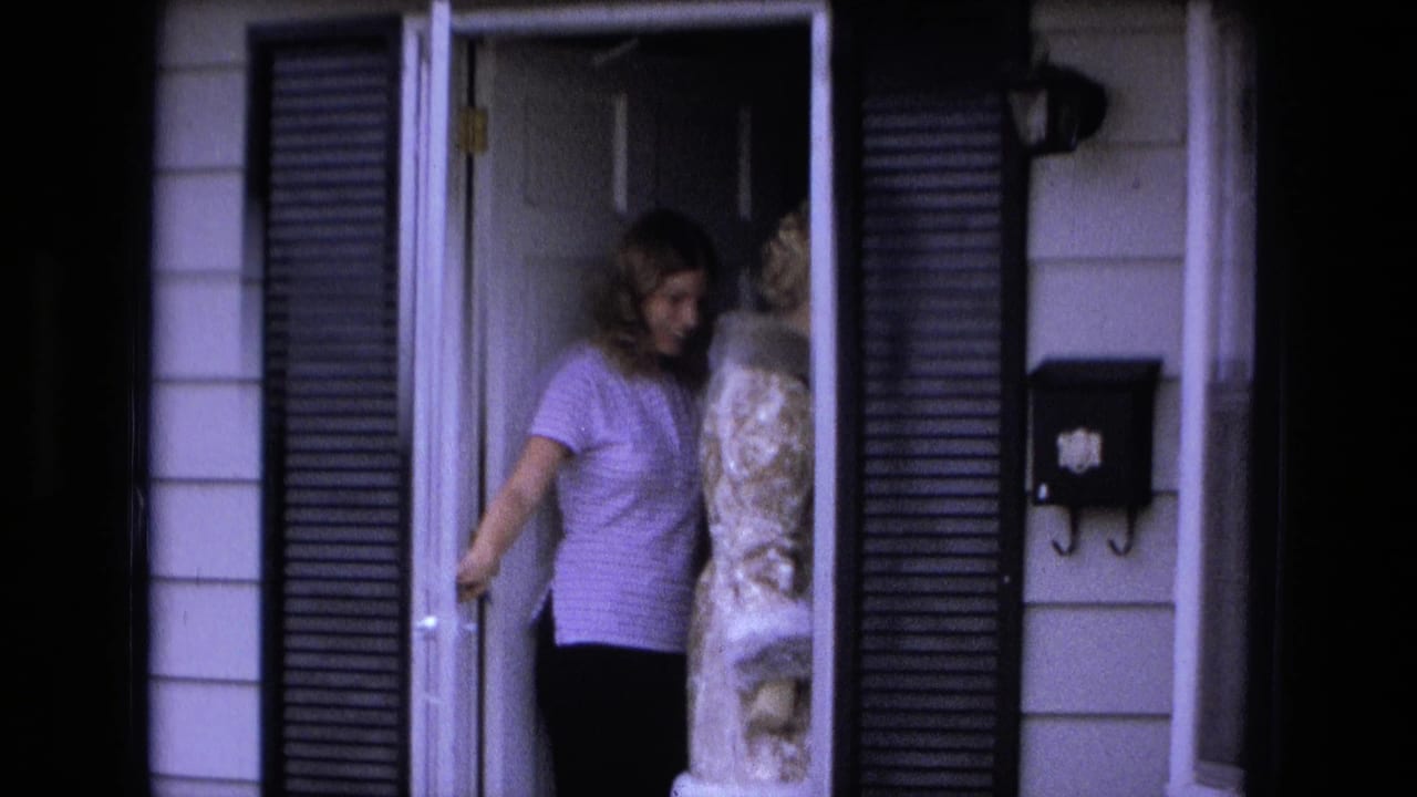 Woman in a purple striped shirt stands in a doorway beside another woman in a patterned coat.