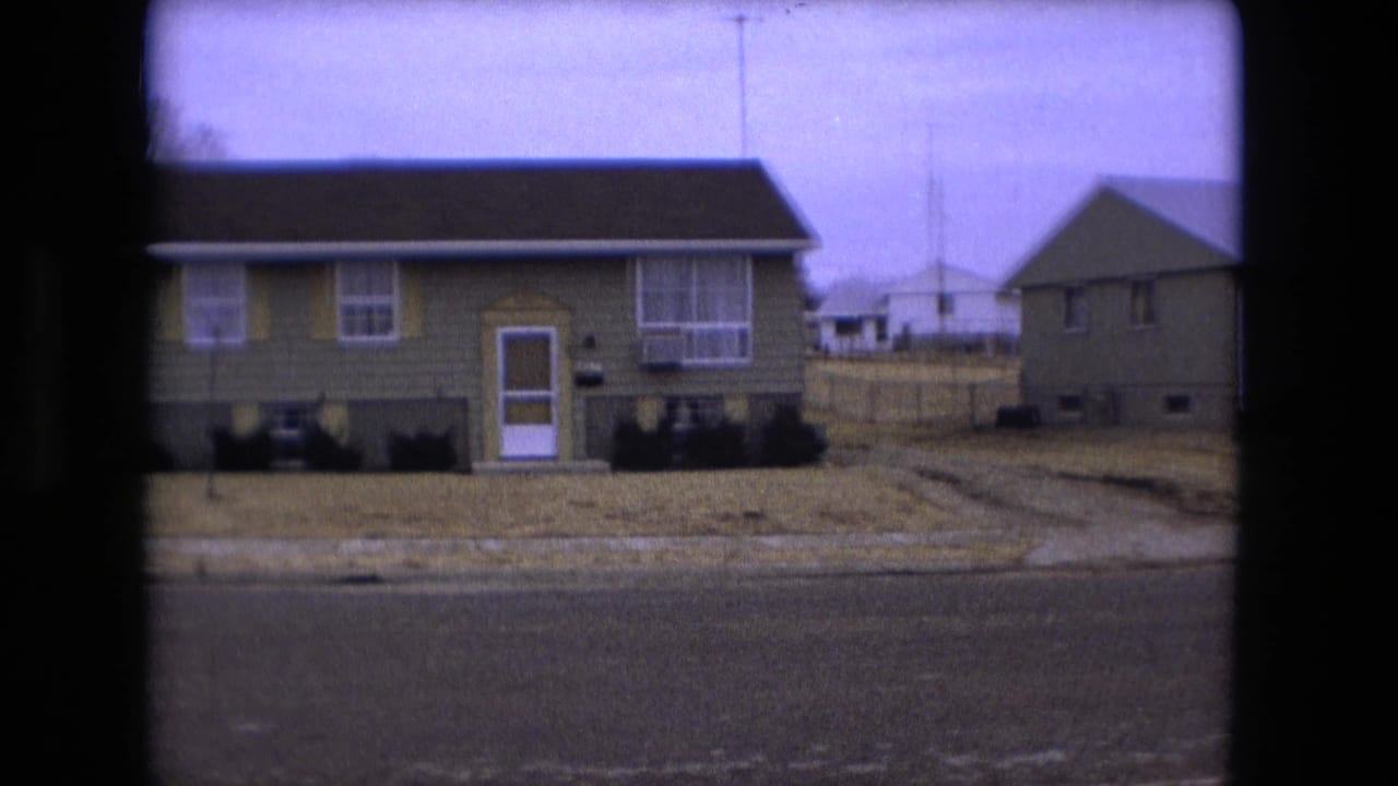 Mid-zoom 1973 Fort Wayne frame with a green residence, white front door, window air conditioner, and adjacent house.