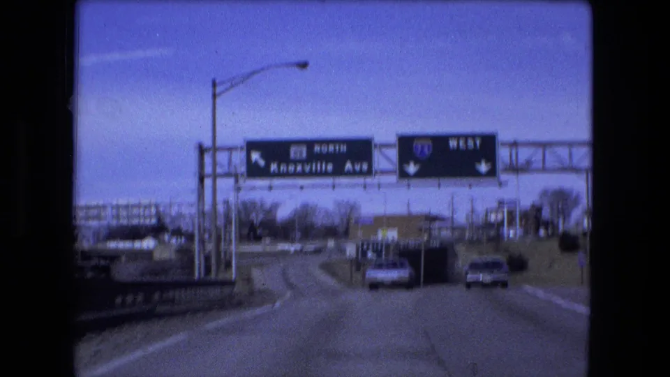 1973 Fort Wayne road footage showing overhead highway signs for Knoxville Avenue and I-74 West above cars on the roadway.