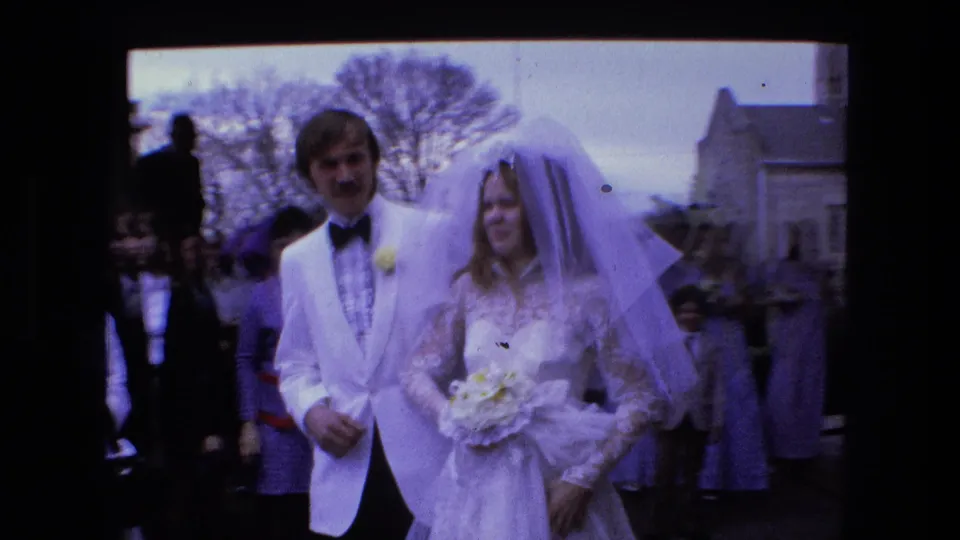 The 1973 Fort Wayne wedding couple is seen amid guests, with the bride holding a bouquet and wearing a long veil.