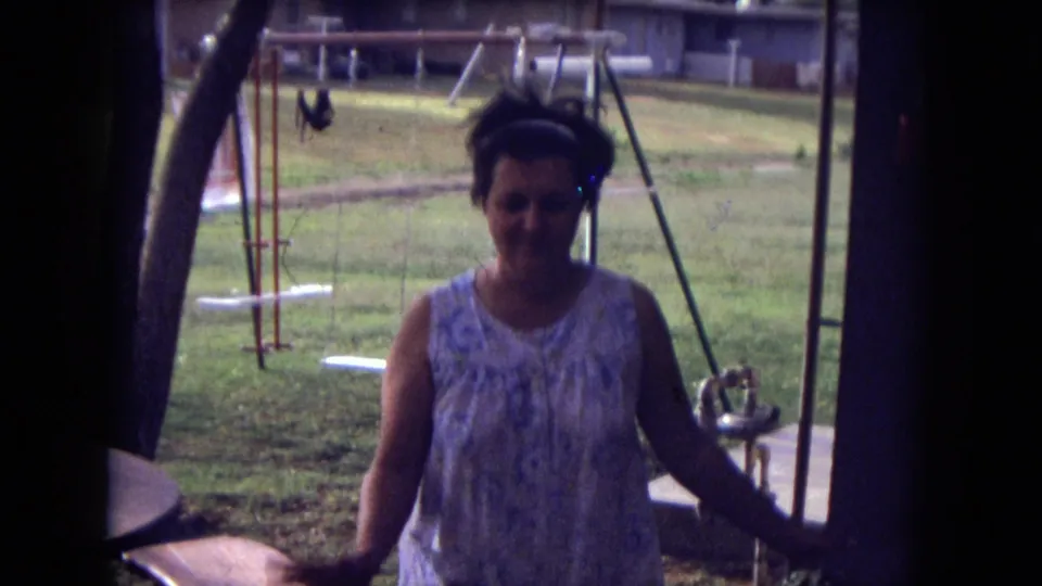 A 1973 8mm backyard frame shows the woman closer to the camera, with trees, swings, lawn, and a house behind her.