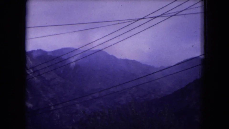 1973 New Mexico forest landscape with distant mountain ridges and multiple utility lines cutting across the upper frame.