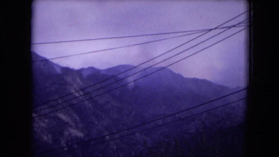 Gila National Forest mountain landscape on 8mm film, with layered slopes, haze, and power lines running across the frame.