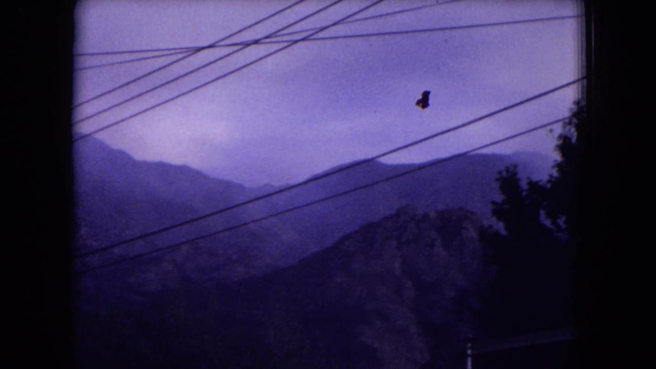 1973 8mm view of hazy mountain ridges in Gila National Forest, New Mexico, crossed by dark overhead power lines.