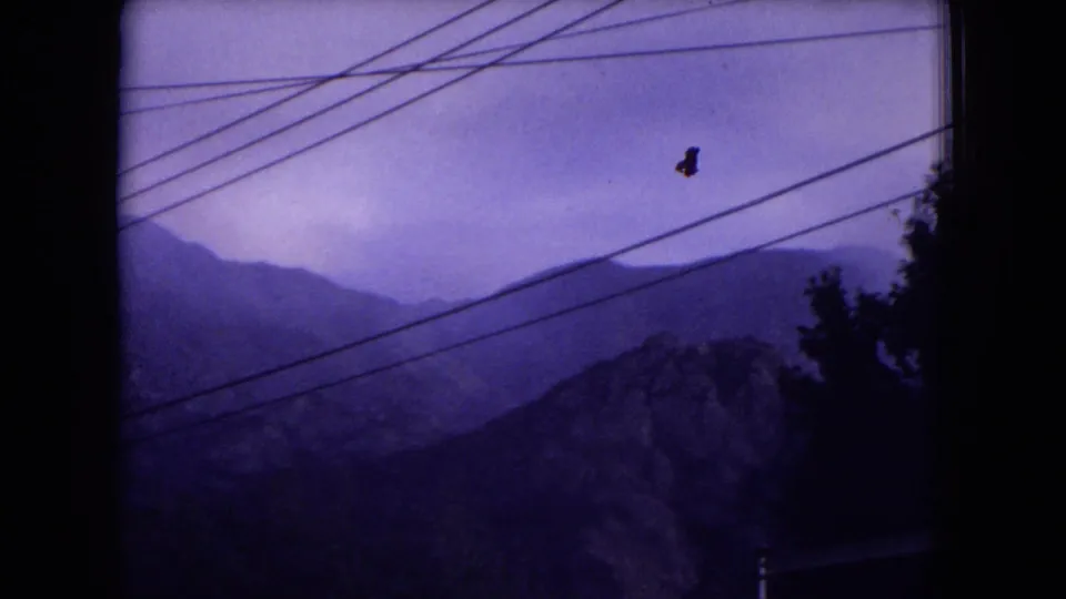 1973 8mm view of hazy mountain ridges in Gila National Forest, New Mexico, crossed by dark overhead power lines.