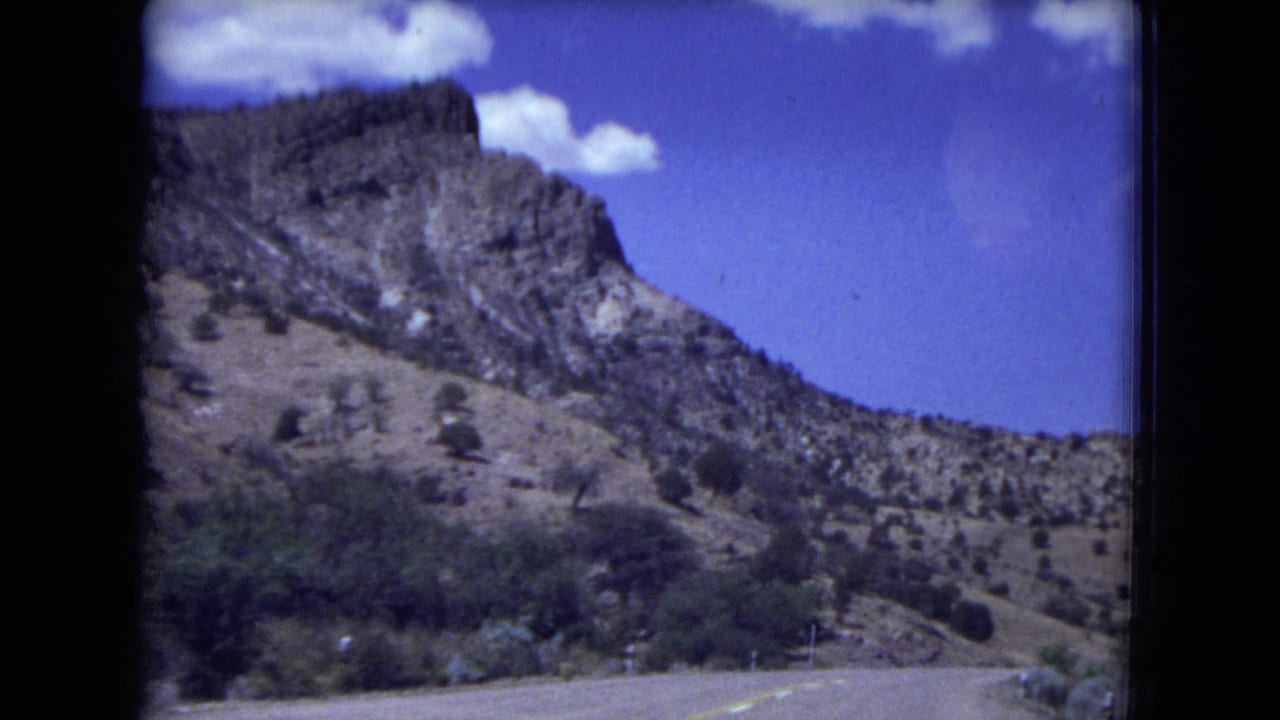 1973 8mm view from a moving vehicle on a road through rocky hills in Gila National Forest, New Mexico.
