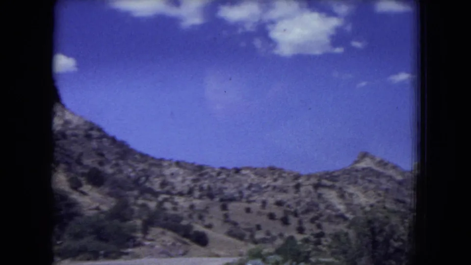 Rocky, scrub-covered terrain in Gila National Forest seen from a moving 8mm home movie camera.