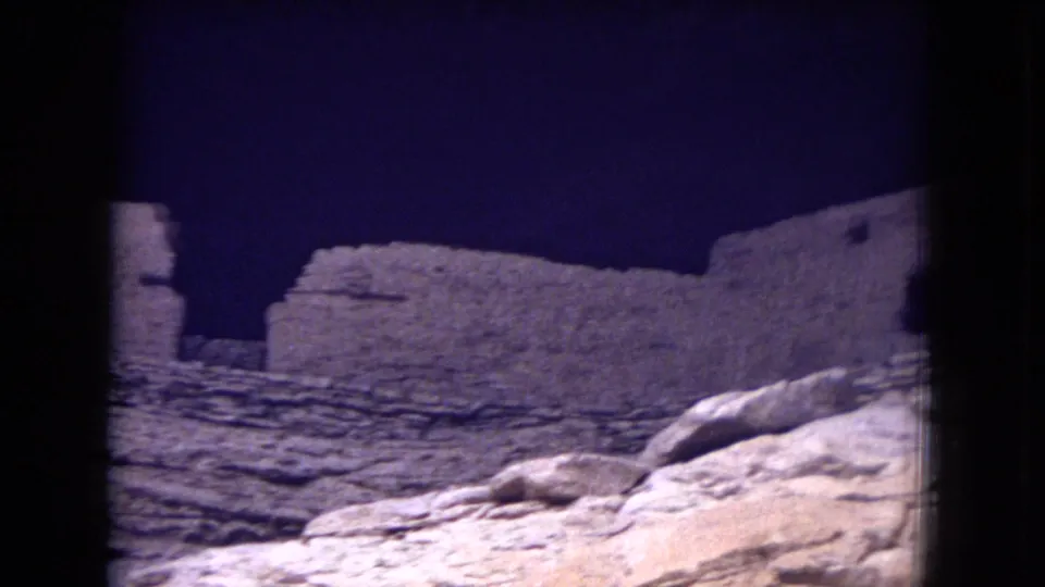 1973 8mm frame showing Gila National Forest stone ruins with pale boulders and a low masonry wall in front.