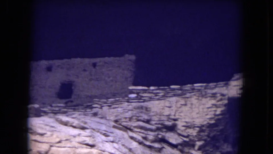1973 Gila National Forest 8mm frame of a pueblo-style stone ruin with a dark rectangular doorway or opening.